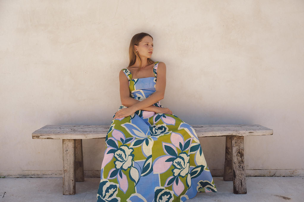 Model in a floral maxi dress seated on a bench